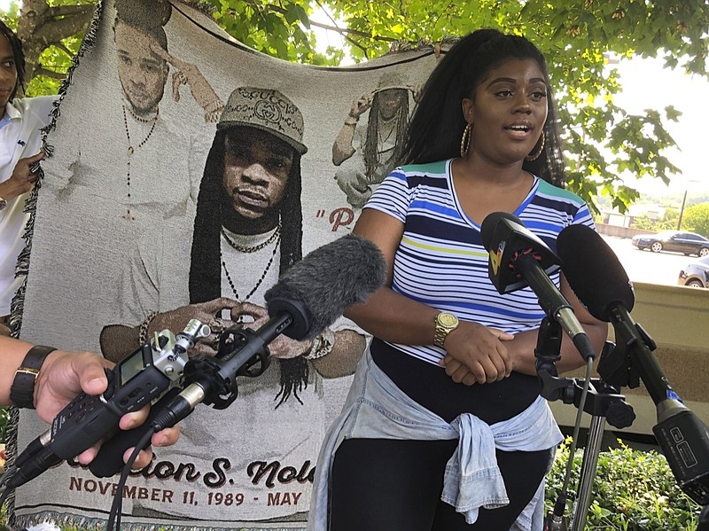 Kayla Cherry speaks at a news conference outside the former headquarters of private prison company CoreCivic, Wednesday, July 10, 2019, in Nashville, Tenn. Cherry's nephew Dameion Nolan, pictured in a blanket behind her, died in May while he was an inmate at CoreCivic-run Whiteville Correctional Facility. (AP Photo/Jonathan Mattise)