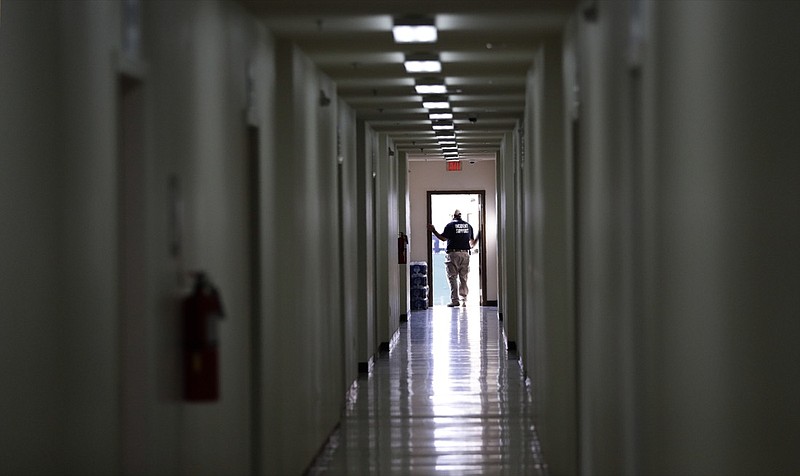 In this Tuesday, July 9, 2019, photo, staff walks through a dormitory at the U.S. government's newest holding center for migrant children in Carrizo Springs, Texas. The government said the holding center will give it much-needed capacity to take in more children from the Border Patrol. (AP Photo/Eric Gay)