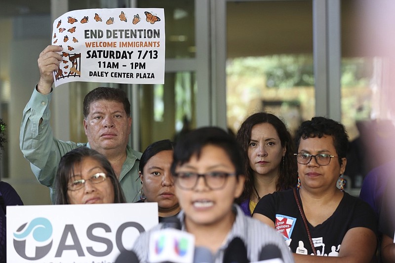 Demonstrators hold placards as Rey Wences, organizer at Organized Communities Against Deportations (OCAD) addresses reporters during a new conference outside the U.S. Citizenship and Immigration Services offices in Chicago, Thursday, July 11, 2019. A nationwide immigration enforcement operation targeting people who are in the United States illegally is expected to begin this weekend. (AP Photo/Amr Alfiky)