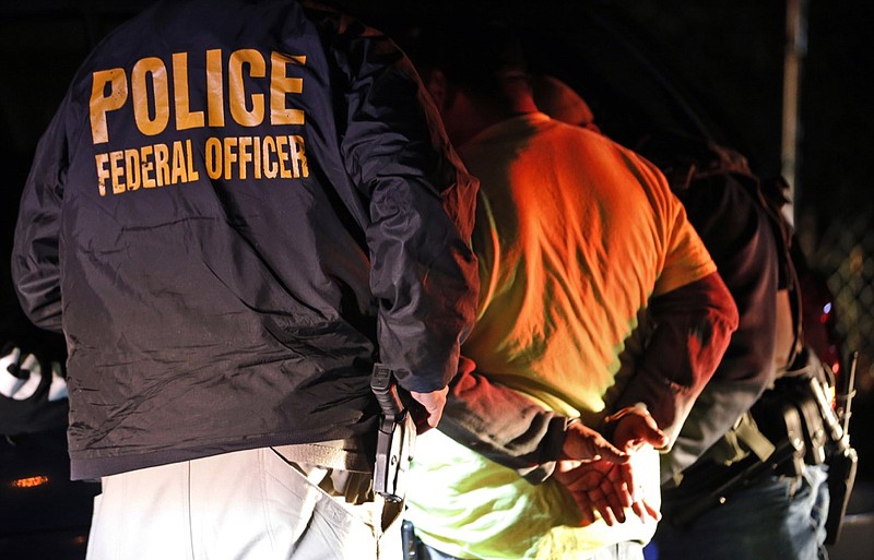 In this Oct. 22, 2018, file photo, U.S. Immigration and Customs Enforcement agents detain a person during a raid in Richmond, Va. The agency is in charge of arresting and deporting immigrants who lack legal status. After postponing an immigration-enforcement operation in June 2019, the Trump administration plans to go ahead with the raids in July. (AP Photo/Steve Helber, File)
