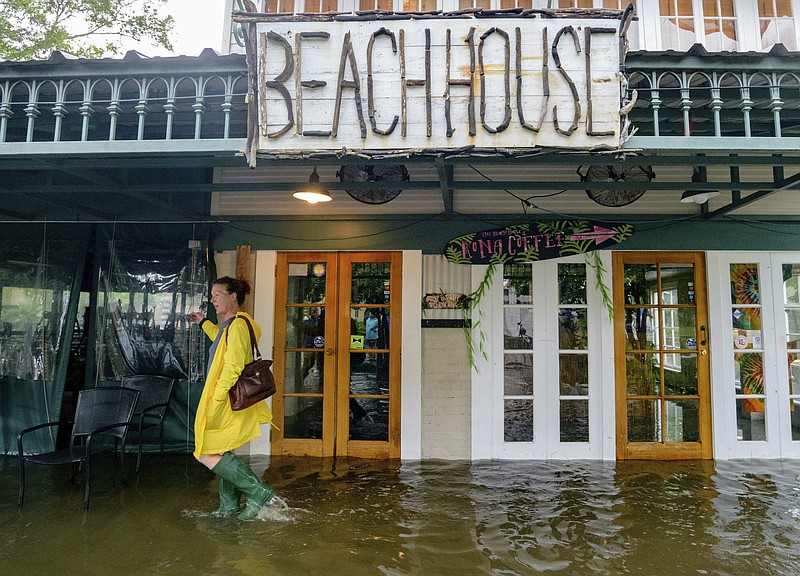 Aimee Cutter, the owner of Beach House restaurant, walks through water surge from Lake Pontchartrain on Lakeshore Drive in Mandeville, La., ahead of Tropical Storm Barry, Saturday, July 13, 2019. Barry is expected to reach hurricane strength by the time its center reaches the Louisiana coast, expected before noon local time. The storm is expected to weaken after it moves inland. (AP Photo/Matthew Hinton)

