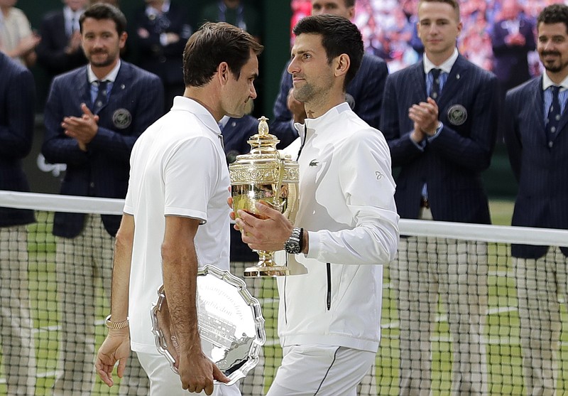 Novak Djokovic, right, holds the winner's trophy as he walks past runner-up Roger Federer after the Wimbledon men's singles final Sunday at the All England Club.
