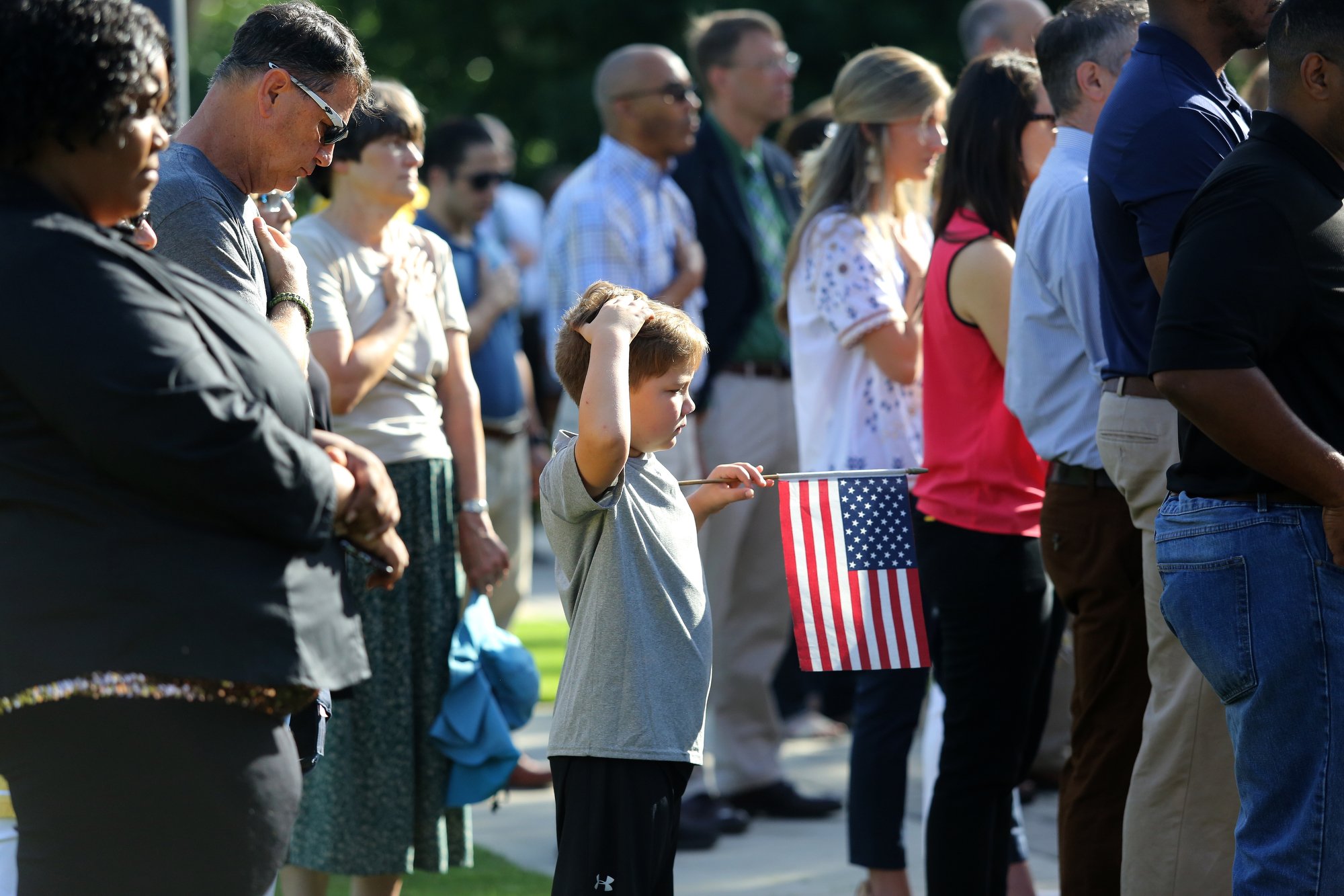 Jackson Thompson, 7, stands holding a flag as his grandfather, Craig Johnson, stands behind him during a ceremony to remember the Fallen Five at Chamberlain Field Pavilion at the University of Tennessee at Chattanooga. Today marked four years since the attack by a lone gunman at a Lee Highway military recruiting center and the Naval Operational Support Center and Marine Corps Reserve Center off of Amnicola Highway.