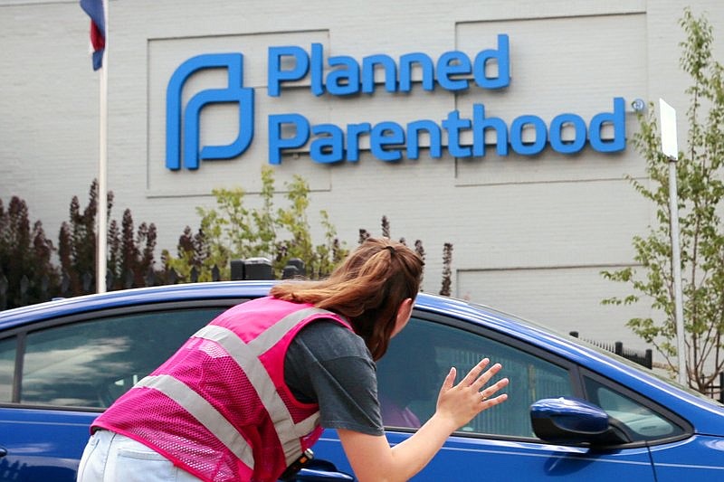 FILE - In this June 28, 2019 file photo, Ashlyn Myers of the Coalition for Life St. Louis, waves to a Planned Parenthood staff member in St. Louis, Mo. The Trump administration says its new regulation barring taxpayer-funded family planning clinics from referring women for abortions is taking effect immediately. (Robert Cohen/St. Louis Post-Dispatch via AP)
