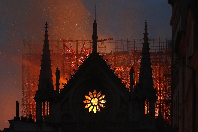 FILE - Flames and smoke rise from Notre Dame cathedral as it burns in Paris, Monday, April 15, 2019.  The city of Paris has ordered a deep cleaning of schools nearest Notre Dame, whose lead roof melted away in the fire last April. (AP Photo/Thibault Camus, File)                                