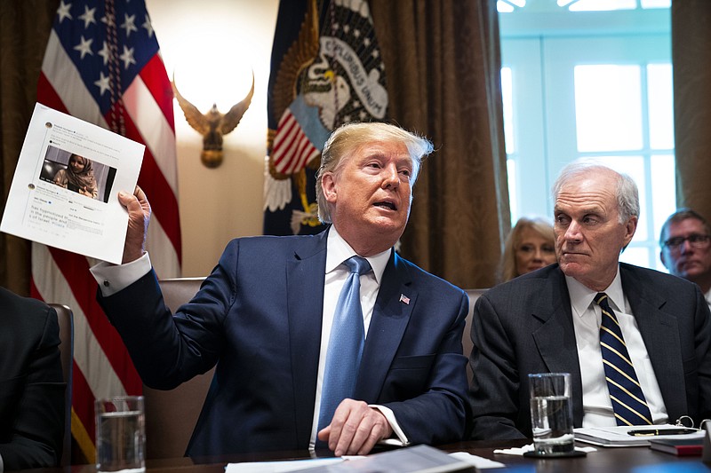 President Donald Trump on Tuesday holds up a photo of Rep. Ilhan Omar, D-Minnesota, during a meeting at the White House, denying that his tweets suggesting she and three other minority congresswomen leave the country were racist. (Doug Mills/The New York Times)