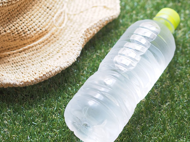 Bottle of mineral water / heatstroke summer elderly senior care heat hot temperatures hat and water bottle on green grass / Getty Images
