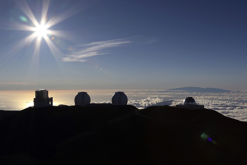 The sun sets Sunday behind telescopes at the summit of Mauna Kea.