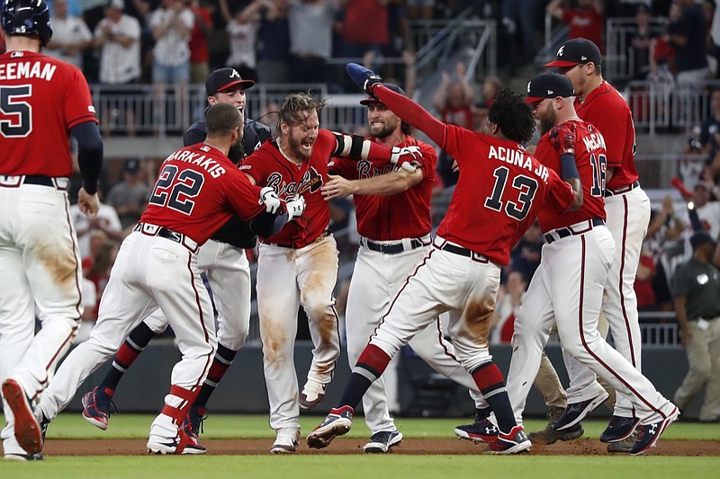 Atlanta Braves third baseman Josh Donaldson, center, is mobbed by teammates after driving in the winning run with a base hit in the ninth inning of Friday night's game against the Washington Nationals.