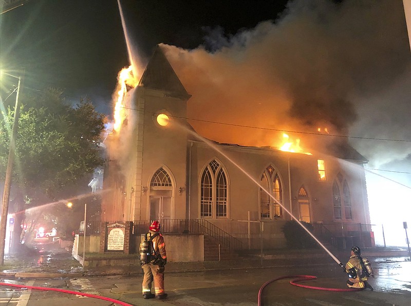 In this Sunday, July 21, 2019, photo released by the Savannah Fire Department, firefighters work to put out a fire at the First Metropolitan Baptist Church, in Savannah, Ga. A house fire in Savannah spread to the church whose pastor was recently accused of sexually abusing a child. Reports say the homes and church were vacant at the time of the fire, and no injuries have been reported. (Savannah Fire Department via AP)