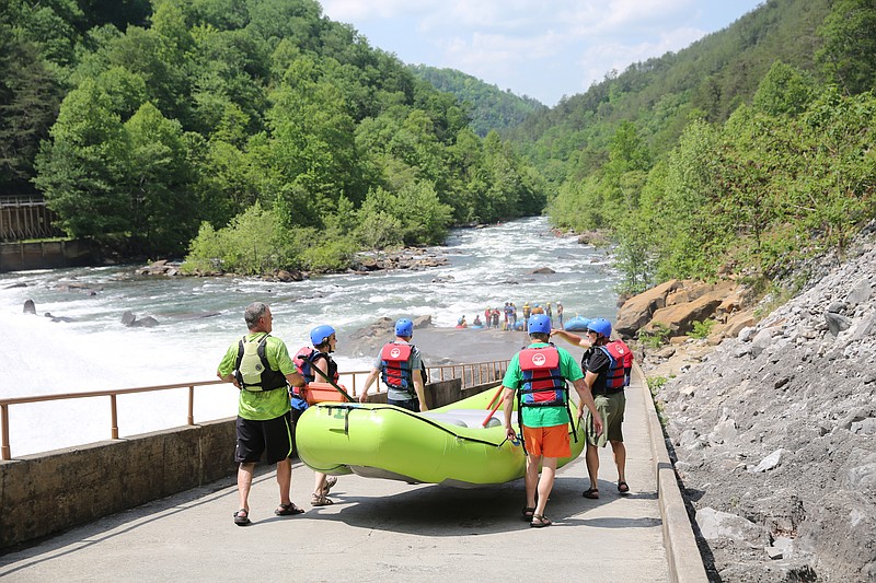 From left, Jimbo Kibler, rafting guide; Melissa Woody, vice president for tourism and development for the Cleveland/Bradley Chamber of Commerce; Brock Hill, deputy commissioner for parks and conservation with the Tennessee Department of Environment and Conservation; Bobby Wilson, executive assistant director of the Tennessee Wildlife Resources Agency; and Sen. Mike Bell take their raft to a launch area as they prepare to take a trip down the Ocoee River after a May 2018 news conference in Benton, Tenn. Guests joined together to recognize the historic public/private partnership securing the future of rafting on the river.