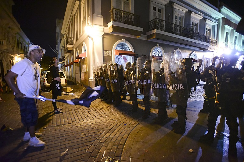 Demonstrators stand in front of riot control units during clashes in San Juan, Puerto Rico, on Monday night.