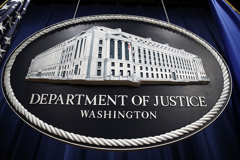 FILE - In this Thursday, April 18, 2019, file photo, a sign for the Department of Justice hangs in the press briefing room at the Justice Department, in Washington. The U.S. Department of Justice is opening a sweeping antitrust investigation of major technology companies and whether their online platforms have hurt competition, suppressed innovation or otherwise harmed consumers. (AP Photo/Patrick Semansky, File)