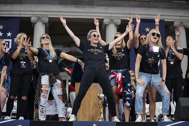 Megan Rapinoe, center, is joined by her teammates on the U.S. women's national soccer team during a celebratory rally at City Hall following a ticker-tape parade in New York on July 10, 2019. (Calla Kessler/The New York Times)