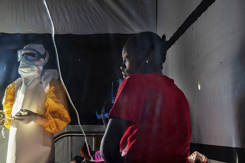 In this Saturday, July 13, 2019 photo, health workers dressed in protective gear check on Ivette Adania, 24, a mother of four whose husband died of Ebola, at a treatment center in Beni, Congo. The World Health Organization has declared the Ebola outbreak an international emergency. More than 1,700 people in eastern Congo have died as the virus has spread in areas too dangerous for health teams to access. (AP Photo/Jerome Delay)