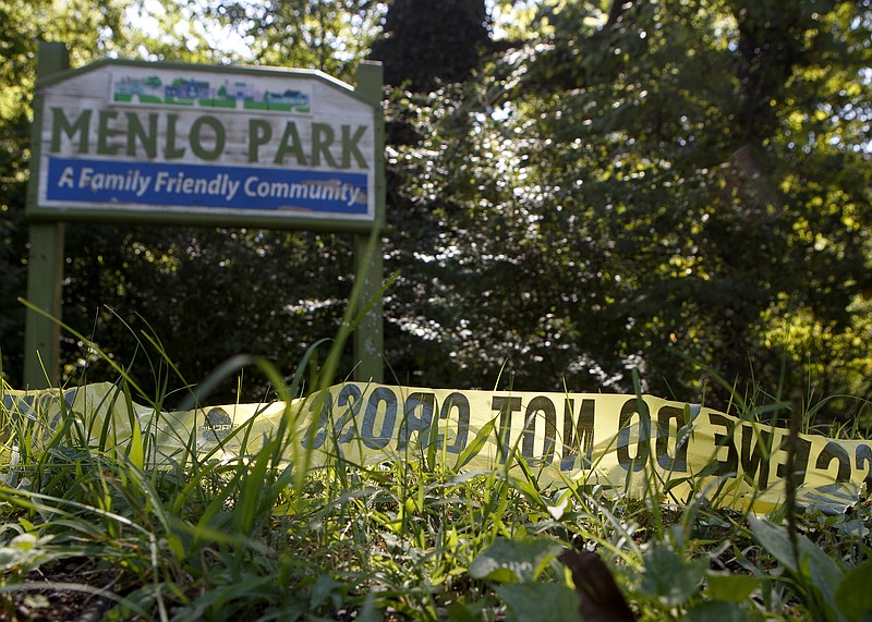 A piece of crime scene tape sits in the grass in front of a sign for the Menlo Park neighborhood at the intersection of Gillespie and Shallowford roads on Friday, July 26, 2019 in Chattanooga, Tenn.