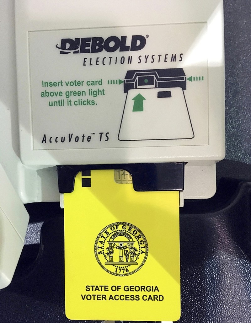 This May 22, 2018, file photo, shows a voter access card inserted in a reader during voting in the Georgia primary in Kennesaw, Ga. A federal judge is set to hear arguments, Thursday, July 25, 2019, in a lawsuit challenging Georgia's outdated voting machines and seeking statewide use of hand-marked paper ballots. The hearing will focus on requests for the judge to order the state to immediately stop using the current voting machines. (AP Photo/Mike Stewart, File)