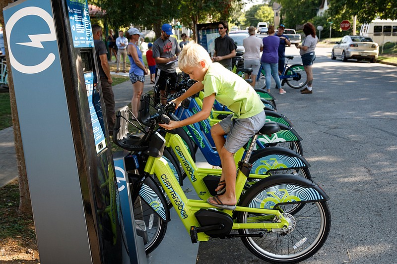 Owen Shaheen checks out a docked bike at the launch of a new Bike Chattanooga bicycle rental station at Tatum Park. The station includes normal rental bikes and electric-assist bikes.