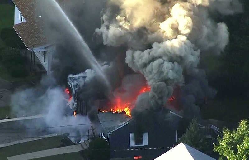 FILE - In this Sept. 13, 2018 file image from video provided by WCVB in Boston, flames consume the roof of a home following an explosion in Lawrence, Mass. Columbia Gas of Massachusetts and its parent, NiSource Inc., announced Monday, July 29, 2019, a settlement had been reached in class action lawsuits resulting from the disaster across several towns north of Boston. (WCVB via AP, File)
