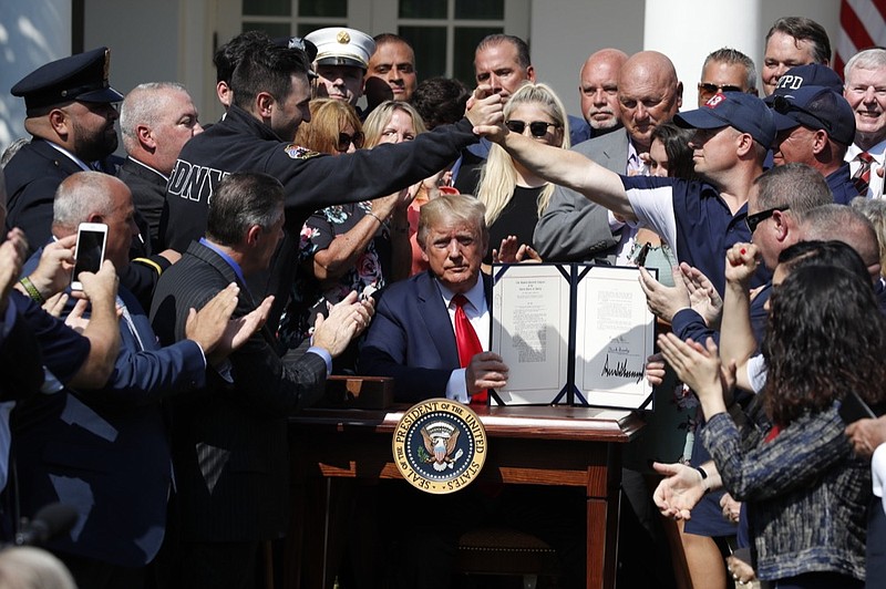 President Donald Trump holds up the signed H.R. 1327 bill, an act ensuring that a victims' compensation fund related to the Sept. 11 attacks never runs out of money, in the Rose Garden of the White House, Monday, July 29, 2019, in Washington. (AP Photo/Alex Brandon)


