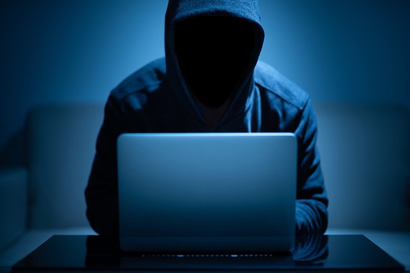 Hacker dark face using laptop in the dark room id theft steal i.d. theft tile / Getty Images
