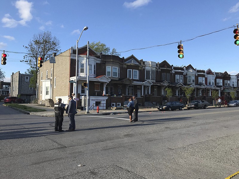 Authorities stand at the Baltimore intersection of Edmondson and Whitmore streets after multiple people were shot in April.