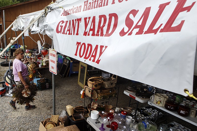 Joanne Denise carries items into the American Haitian Foundation tent along Taft Highway for the 127 Yard Sale on Wednesday, July 31, 2019 in Walden, Tenn. The 127 Yard Sale, or the World's Longest Yard Sale, starts today and runs through Sunday. The route covers 690 miles from Addison, Michigan, to Gadsden, Alabama, with thousands of roadside vendors along the route. Local residents should allow extra time for traveling. Traffic is always slow-going over Signal Mountain then through downtown before the route picks back up on scenic Lookout Mountain Parkway to Gadsden. / Staff photo by C.B. Schmelter 