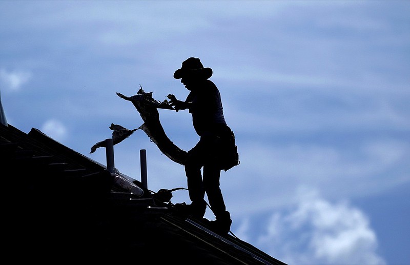 In this July 18, 2019, file photo a roofer works on a new home under construction in Houston. On Wednesday, July 31, the Labor Department reports on wages and benefits for U.S. workers during the April-June quarter. (AP Photo/David J. Phillip, File)