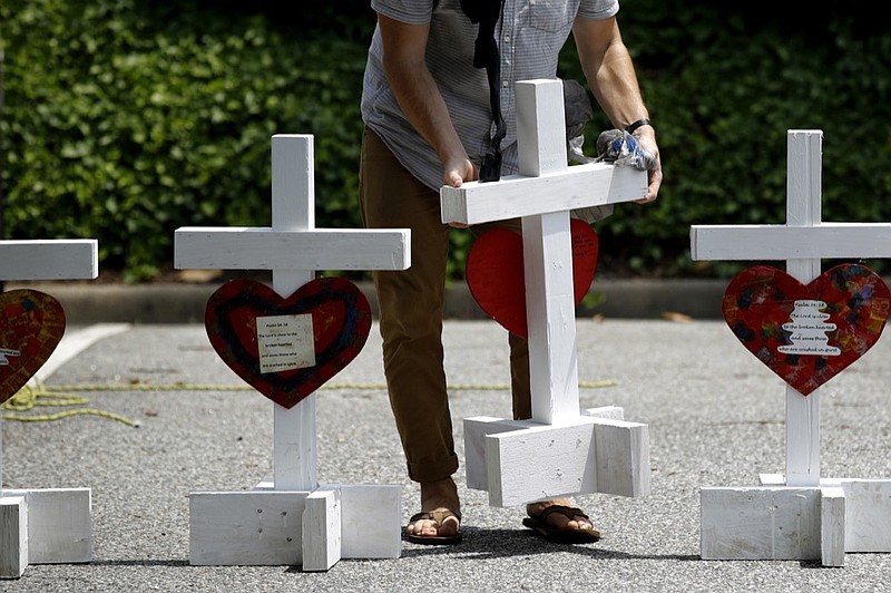 FILE - In this June 2, 2019, file photo, a volunteer prepares to place crosses for victims of a mass shooting at a municipal building in Virginia Beach, Va., at a nearby makeshift memorial. The U.S. has recorded nearly 20 mass killings so far this year, including the one in Virginia Beach, the majority of them domestic violence massacres that receive scant national attention compared to high-profile public shootings at schools, churches and concerts in recent years. (AP Photo/Patrick Semansky, File)