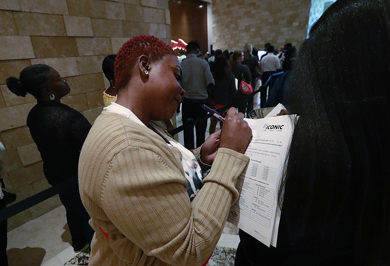 In this June 4, 2019 photo, job applicant Esta Williams, center, uses Tracy Simeton's back to fill out a questionnaire as they wait in line at the Seminole Hard Rock Hotel & Casino Hollywood during a job fair in Hollywood, Fla. On Friday, Aug. 2, the U.S. government issues the July jobs report. (AP Photo/Wilfredo Lee, File)