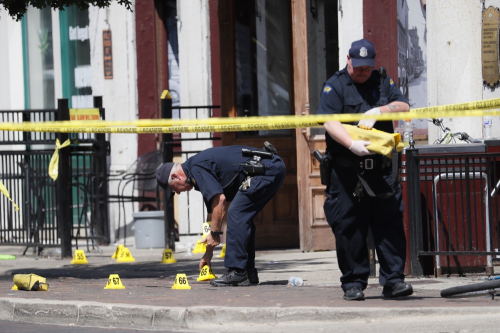 Authorities retrieve evidence markers at the scene of a mass shooting, Sunday, Aug. 4, 2019, in Dayton, Ohio. Multiple people in Ohio have been killed in the second mass shooting in the U.S. in less than 24 hours, and the suspected shooter is also deceased, police said. (AP Photo/John Minchillo)
