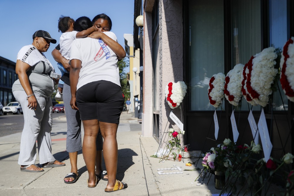 Family members of slain mass shooting victim Thomas “TJ” McNichols, from left, Donna Johnson, aunt, and sisters Jamila and Finesse McNichols, mourn beside a memorial near the scene of the crime, Monday, Aug. 5, 2019, in Dayton, Ohio. (AP Photo/John Minchillo)