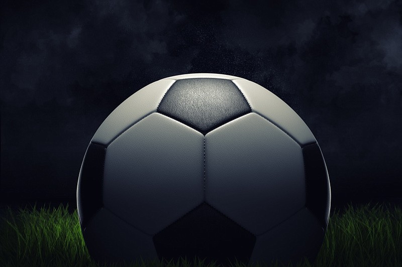 3d rendering of a single football ball standing on a grass field on a dark background. Football field. Scoring goal. Sport under projectors. soccer tile / Getty Images