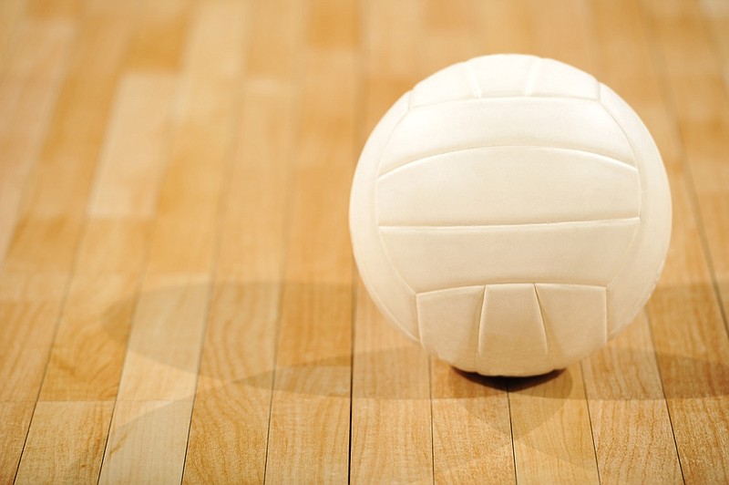 A lone white volleyball sitting on a wooden floor - stock photo