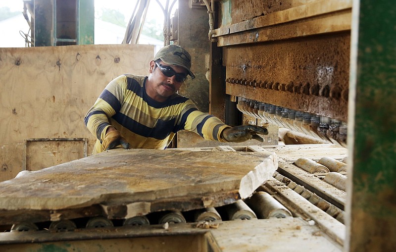 Orlando Lopez, a production employee with Majestic Stone, pushes a piece of stone into a machine to cut into smaller pieces Tuesday, July 24, 2018, at Majestic Stone in Dayton, Tennessee.