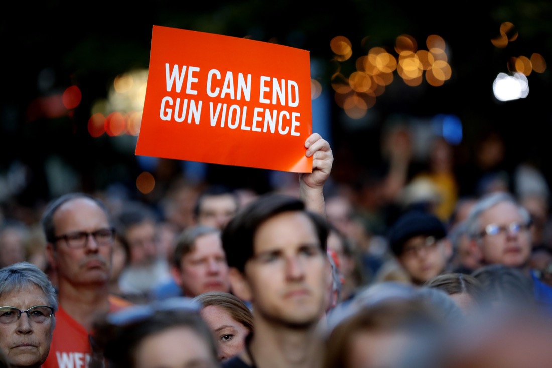 Mourners gather for a vigil at the scene of a mass shooting, Sunday, Aug. 4, 2019, in Dayton, Ohio. A masked gunman in body armor opened fire early Sunday in the popular entertainment district in Dayton, killing several people, including his sister, and wounding dozens before he was quickly slain by police, officials said. (AP Photo/John Minchillo)