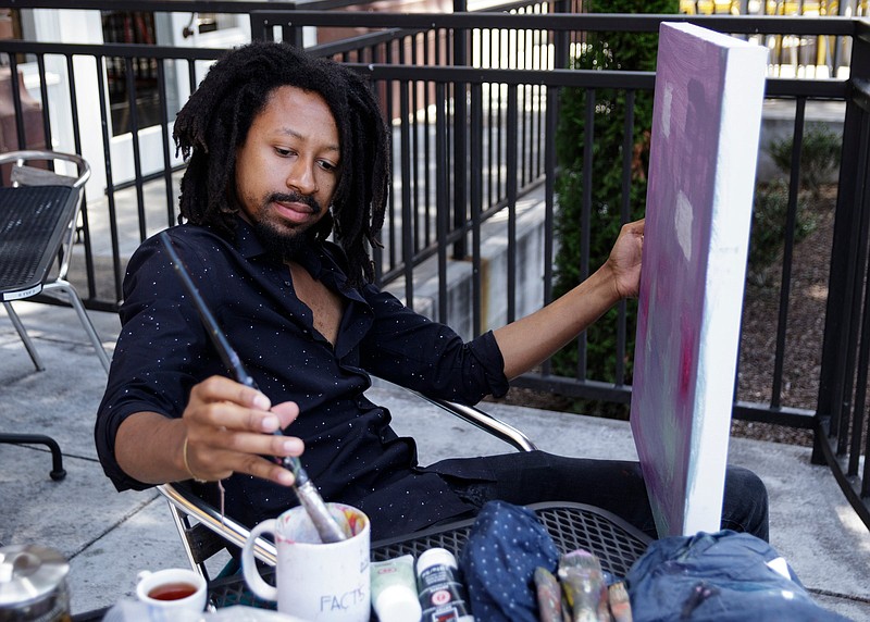 Artist Genesis the Greykid works on a painting outside the Frothy Monkey coffee shop on Tuesday, July 24, 2018, in Chattanooga, Tenn. 