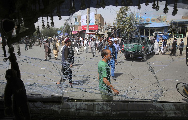 Afghans are seen through a shattered glass of the transport bus broken after an explosion in Kabul, Afghanistan, on Wednesday.