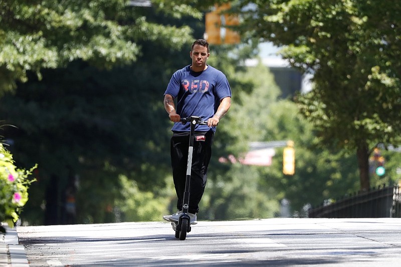 A man rides a electric scooter Thursday, Aug. 8, 2019, in Atlanta. Atlanta is banning electric scooters during nighttime hours during a deadly summer for riders. In Atlanta, three riders have died since May in crashes that involved a public bus, an SUV and a car. Police in the Atlanta suburb of East Point say a fourth rider was killed there Tuesday in a collision involving his scooter and a truck. (AP Photo/John Bazemore)