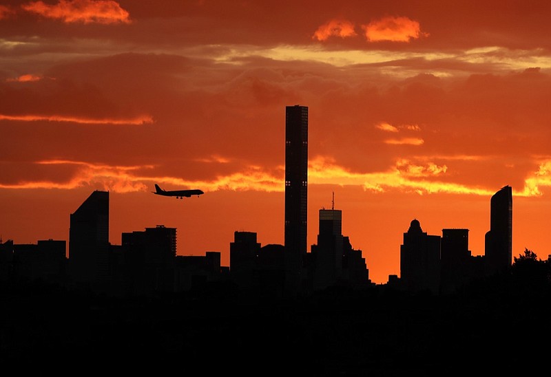 In this Sept. 6, 2016, file photo, a plane flies near the Manhattan skyline at sunset in New York. The latest mass shootings in the United States have triggered multiple countries to warn their citizens to be wary of travel conditions there. (AP Photo/Darron Cummings, File)