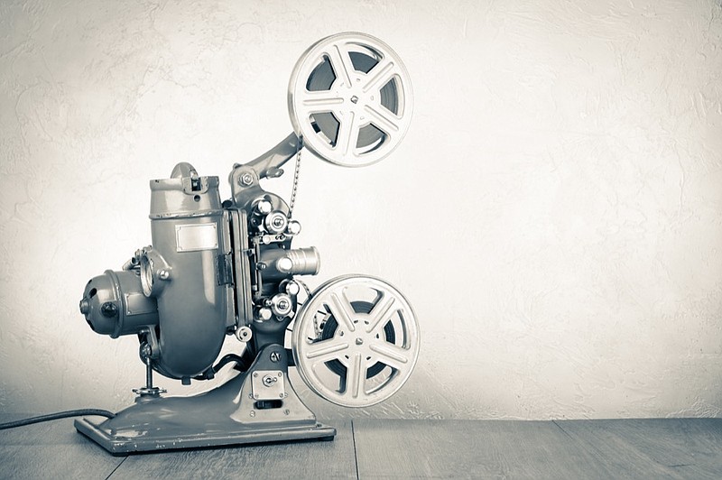 Retro old reel movie projector for cinema. Vintage style sepia photo film tile movie tile silent film / Getty Images
