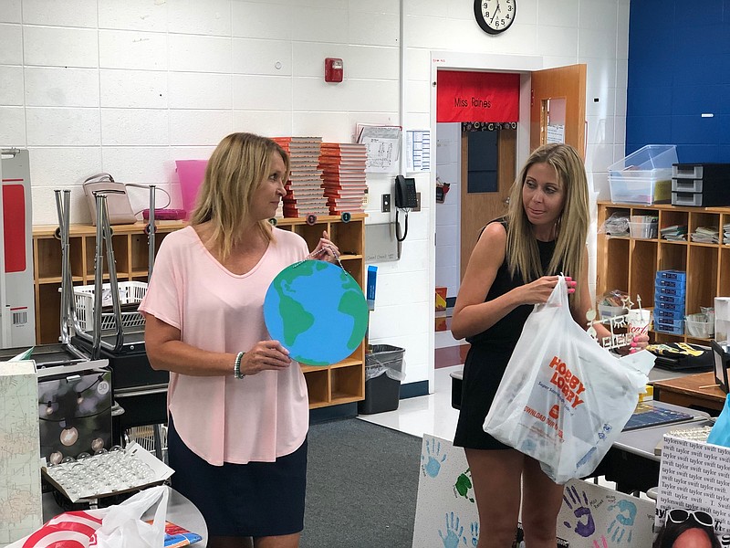 Patti Raines, left, helps daughter Amanda Raines decorate her third-grade classroom at Woodstation Elementary. Such efforts come at teachers' expense. Amanda Raines said the cost to convert her classroom theme from "Harry Potter" to travel adventures was around $200. / Staff photo by Davis Lundy