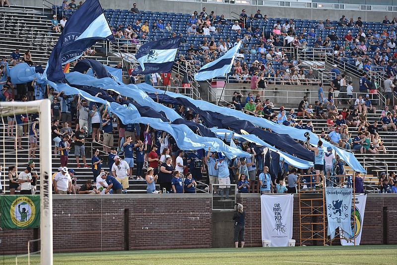 Chattanooga Football Club fans raise flags before the game against the New York Cosmos in the opener to the NPSL Members Cup at Finley Stadium.