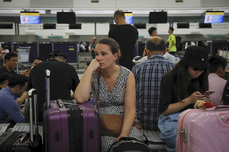 Australian Penny Tilley, center, reacts next to stranded travelers at the closed check-in counters at the Hong Kong International Airport, Monday, Aug. 12, 2019. One of the world's busiest airports canceled all flights after thousands of Hong Kong pro-democracy protesters crowded into the main terminal Monday afternoon. (AP Photo/Kin Cheung)