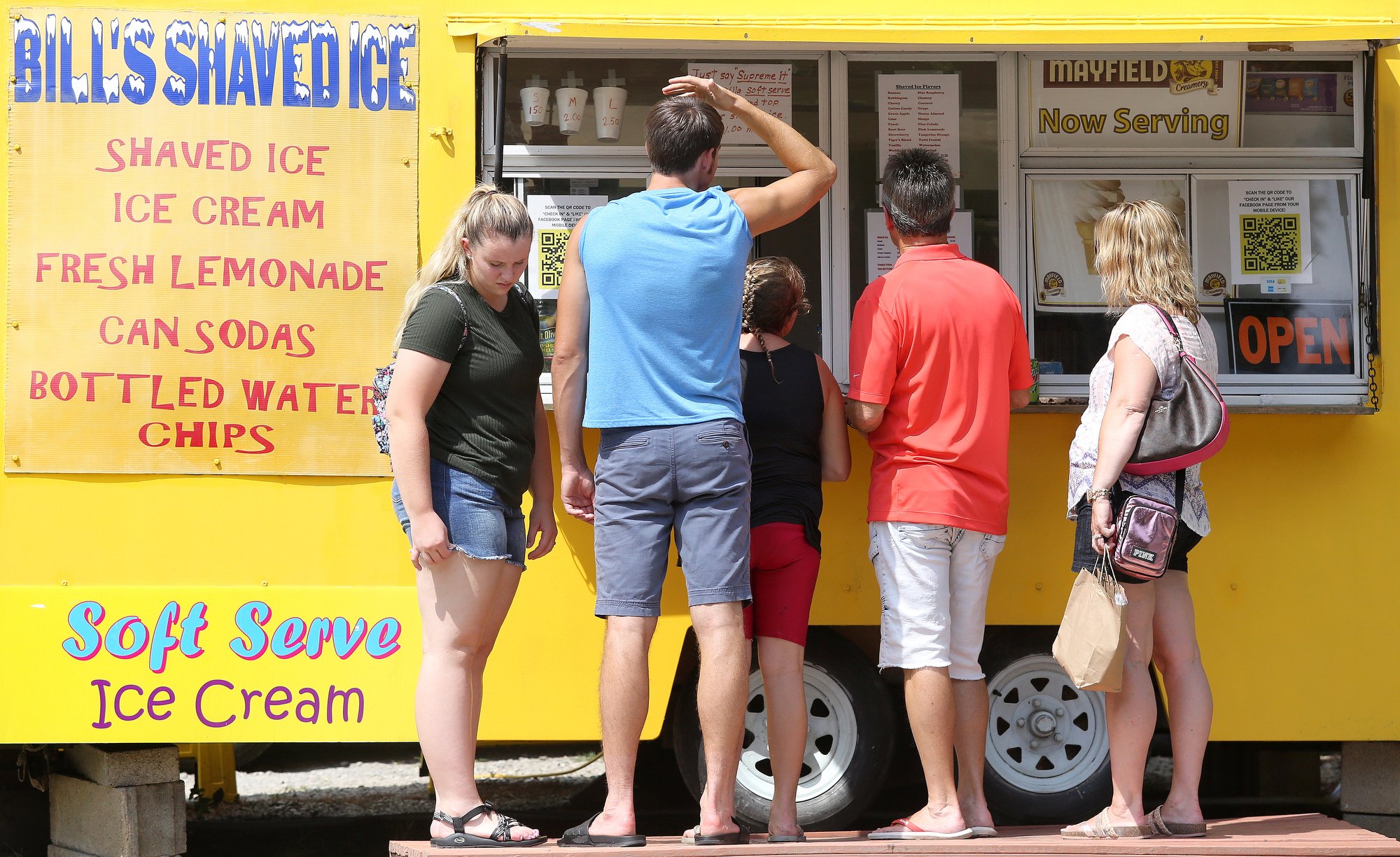 Staff photo by Erin O. Smith / A family stops by Bill's Shaved Ice Monday, August 12, 2019 at Coolidge Park in Chattanooga, Tennessee. The owner of Bill's Shaved Ice, Bill Henderson, says that he sees the most customers when locals brings their kids to the fountain in Coolidge Park to cool off. The heat index on Tuesday is forecast to be over 100.