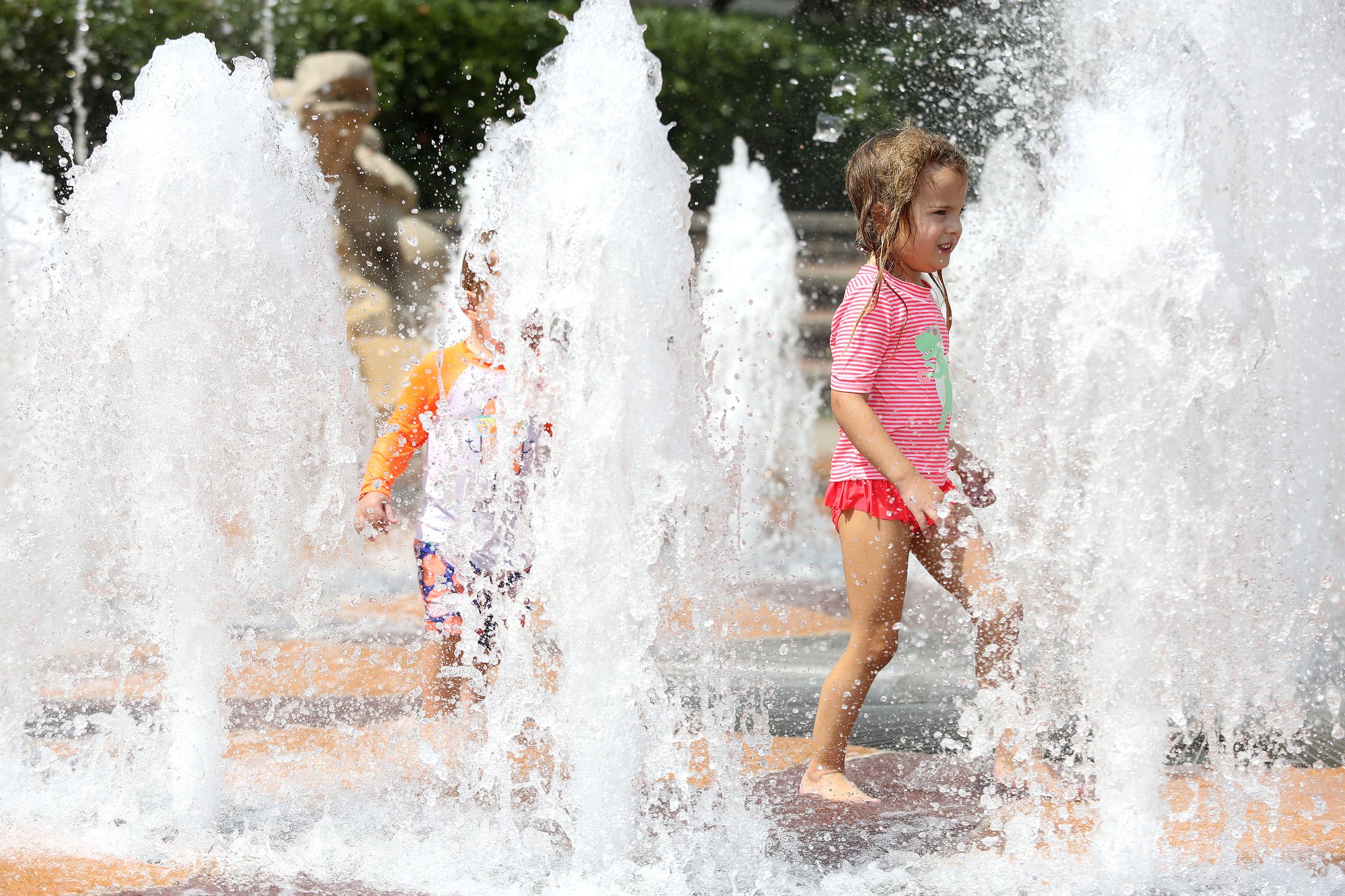 Staff photo by Erin O. Smith / John Michael Sabourin, 2, and Mary Katherine Sabourin, 4, play in the fountain Monday, August 12, 2019 at Coolidge Park in Chattanooga, Tennessee. The Sabourin family lives just across the river from Coolidge Park and makes regular trips to the take advantage of the fountain. The heat index on Tuesday is forecast to be over 100.