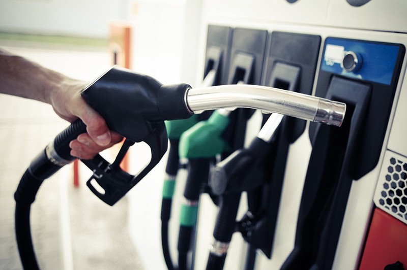 Detail of a hand holding a fuel pump at a station gas tile gasoline gas pump tile / Getty Images
