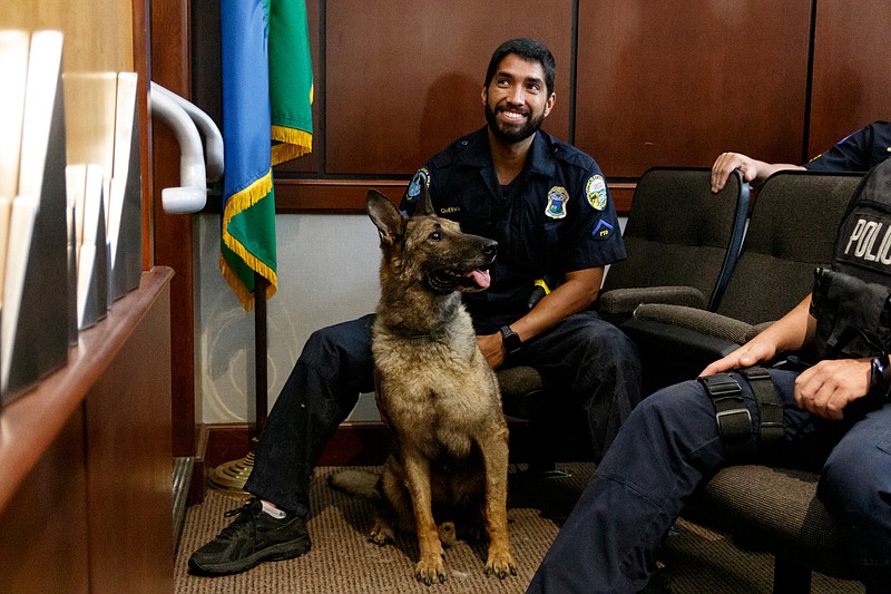 Staff photo by Doug Strickland/ K9 Kilo sits with his handler, Officer George Romero, during an agenda session at the Chattanooga City Council chambers on Tuesday, Aug. 13, 2019, in Chattanooga, Tenn. K9 Kilo is retiring after ten years of service to live permanently with his handler, Officer George Romero.