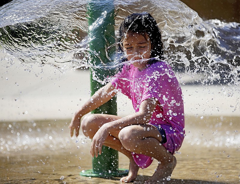 Abigail Sisney, 8, cools down from the hot weather in the splash pad at Rayola Park in Owasso, Okla., Monday, Aug. 12, 2019. (Mike Simons/Tulsa World/Tulsa World via AP)