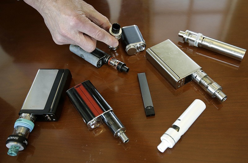 FILE - In this Tuesday, April 10, 2018 photo, a high school principal displays vaping devices that were confiscated from students at the school in Massachusetts. On Wednesday, Aug. 14, 2019, the Vapor Technology Association filed a lawsuit against the U.S. government to delay a review of electronic cigarettes. (AP Photo/Steven Senne)